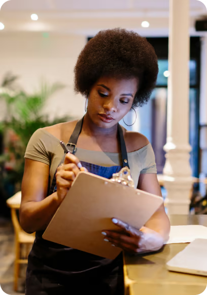 Photo image showing a restaurant worker writing something on a clipboard